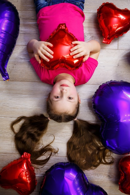 Niña en camiseta rosa juega con globos