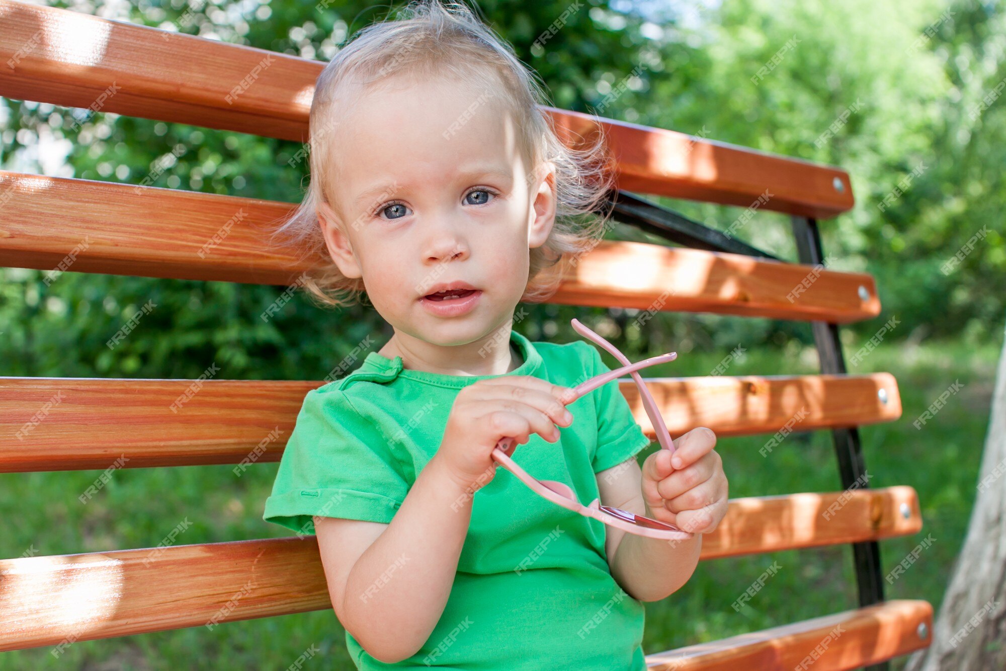 Niña con una camiseta verde y una panamá rosa camina en el parque en el  verano