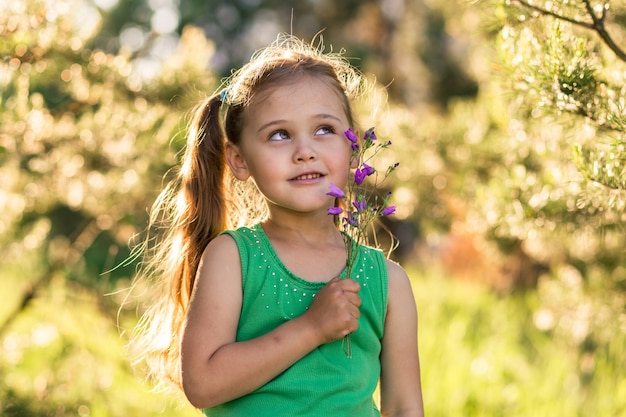 niña con campanas de flores en la naturaleza en verano