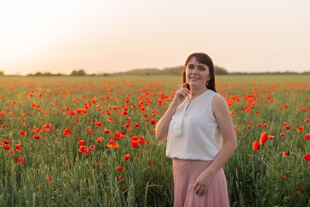 Una niña en un campo con amapolas en flor al atardecer Horario de verano