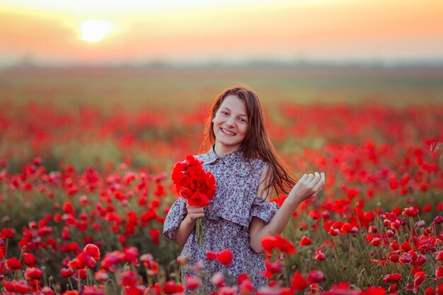 una niña en un campo con amapolas en las manos sonríe