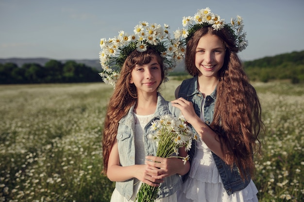 Niña en un campo de flores de margarita. Niñas en una corona de margaritas blancas, el concepto y la idea de una infancia feliz