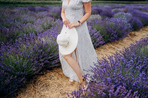 Una niña en un campo de lavanda sostiene un sombrero blanco en sus manos