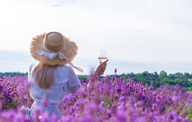 Una niña en un campo de lavanda vierte vino en un vaso Relajación