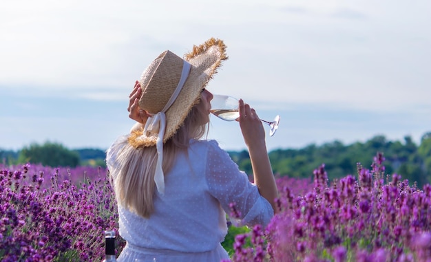 Una niña en un campo de lavanda vierte vino en un vaso Relajación