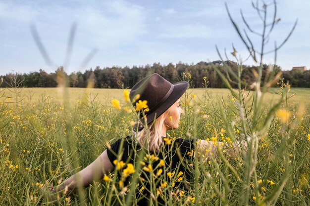 Una niña en un campo lleno de altas flores amarillas al atardecer.