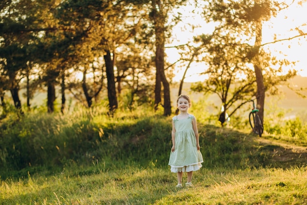 Niña en un campo con rollos de heno al atardecer