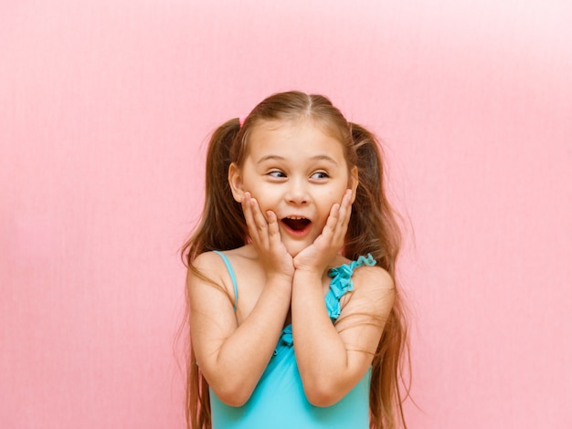 Foto niña con una cara sorprendida sobre un fondo rosa