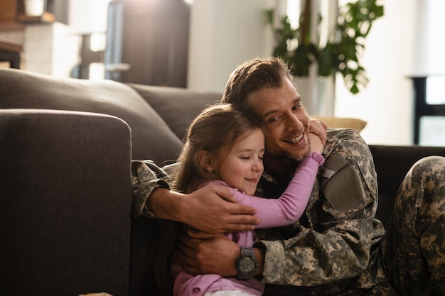 Niña cariñosa abrazando a su padre militar con los ojos cerrados en casa El foco está en el padre