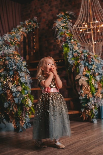 Niña carismática con un vestido brillante en el fondo de las decoraciones navideñas