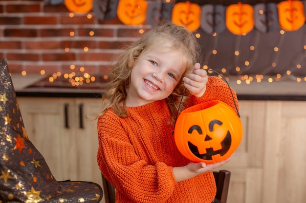 Niña en casa en la cocina en la mesa con una calabaza para halloween