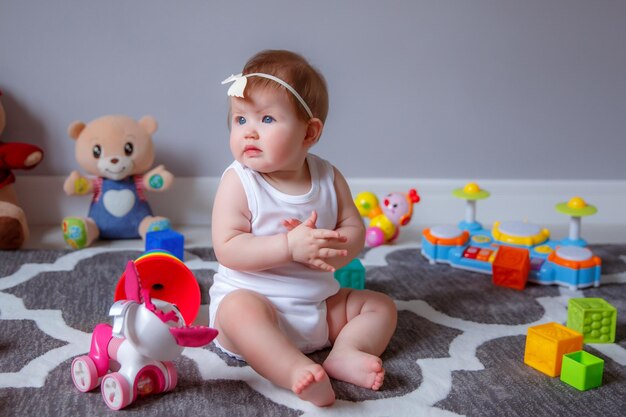 Niña en casa sentada en el suelo jugando con juguetes