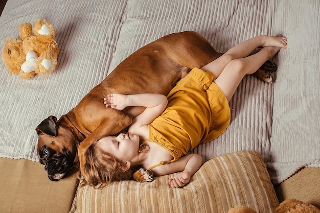 la niña en casa en el sofá se va a la cama con su perro grande