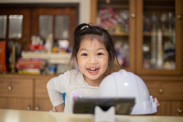 Niña con casco de ingeniero blanco en casa