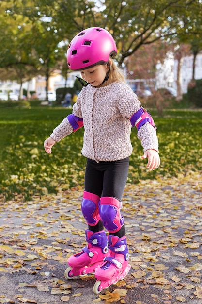 Foto niña con casco en patines de protección en el parque