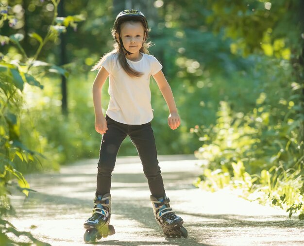 Una niña con casco protector patinando en el parque sobre sus ruedas