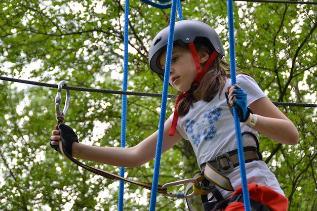 Una niña con casco trepa por una cuerda.