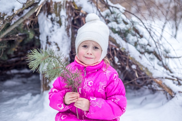 Niña caucásica de 5 años jugando en el bosque de invierno, pasar tiempo al aire libre en invierno