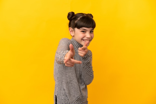 Niña caucásica aislada apuntando hacia el frente y sonriendo