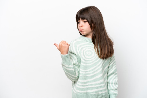 Niña caucásica aislada de fondo blanco infeliz y apuntando hacia un lado