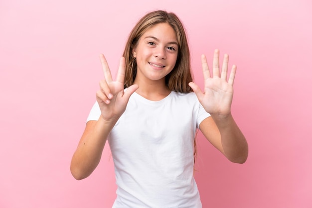 Niña caucásica aislada de fondo rosa contando ocho con los dedos