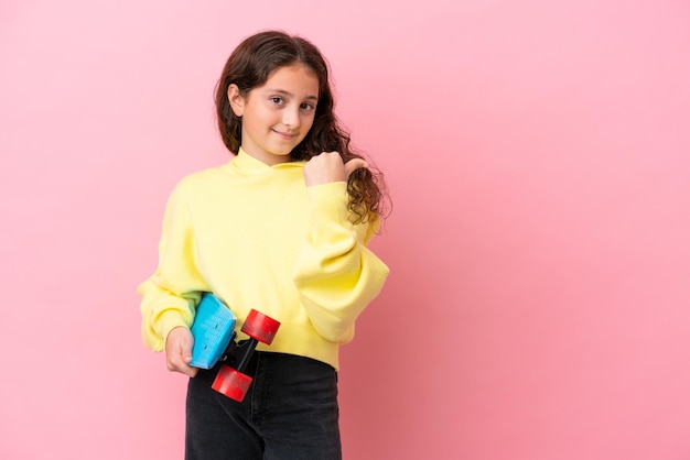 Niña caucásica aislada de fondo rosa con un patín y apuntando hacia un lado