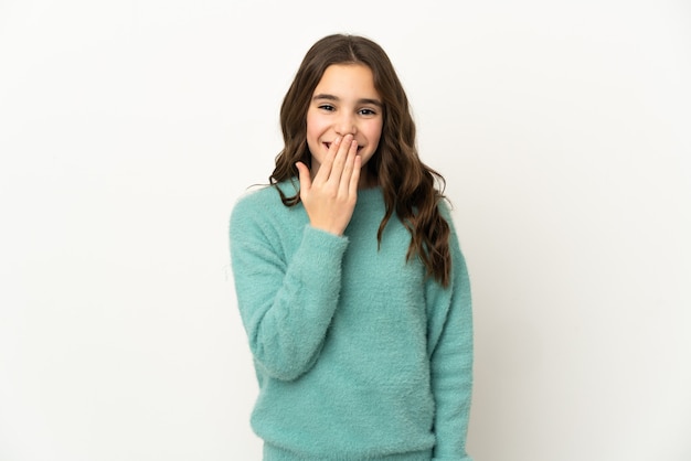 Niña caucásica aislada en la pared blanca feliz y sonriente cubriendo la boca con la mano