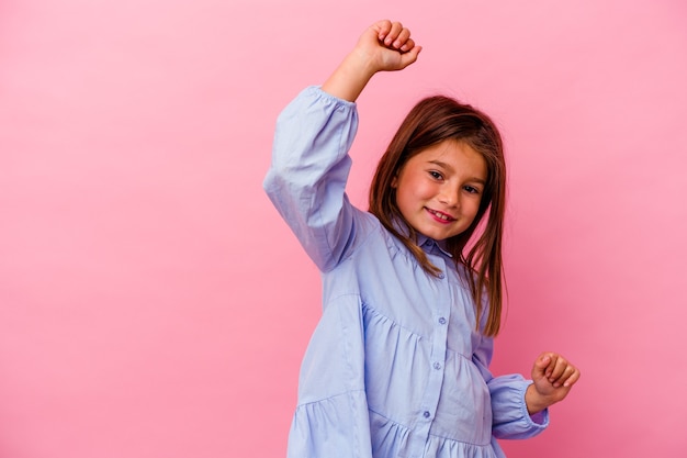 Foto niña caucásica aislada en pared rosa celebrando un día especial, salta y levanta los brazos con energía.