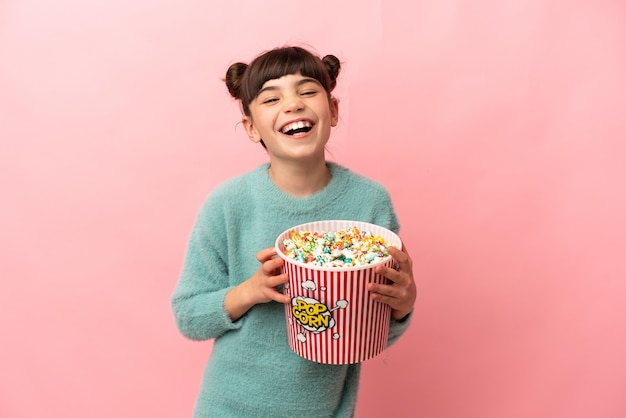 Niña caucásica aislada en rosa sosteniendo un gran cubo de palomitas de maíz