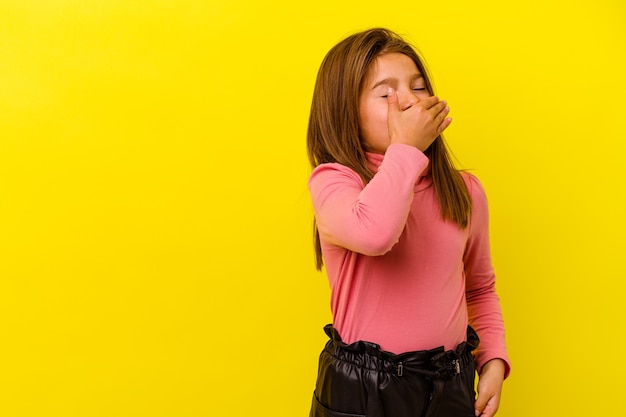 Niña caucásica aislada sobre fondo amarillo riendo feliz, despreocupada, emoción natural.