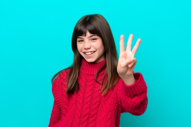 Niña caucásica aislada sobre fondo azul feliz y contando tres con los dedos