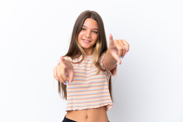 Foto niña caucásica aislada sobre fondo blanco apuntando al frente con expresión feliz