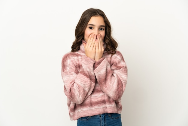 Niña caucásica aislada sobre fondo blanco feliz y sonriente cubriendo la boca con las manos