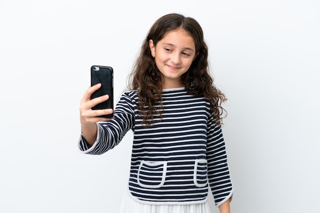 Niña caucásica aislada sobre fondo blanco haciendo un selfie