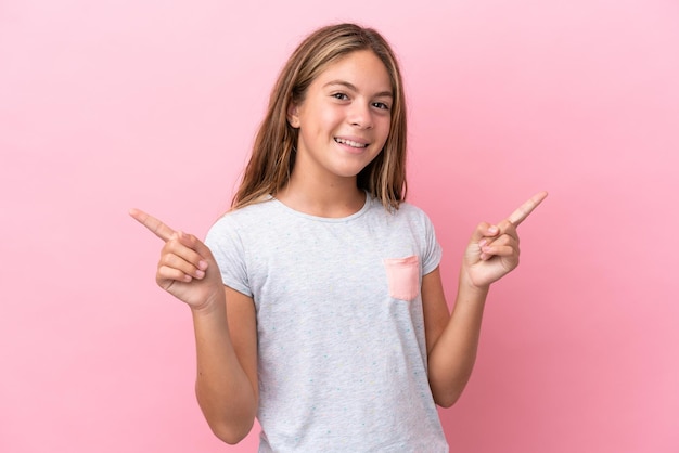 Niña caucásica aislada sobre fondo rosa dedo acusador a los laterales y feliz