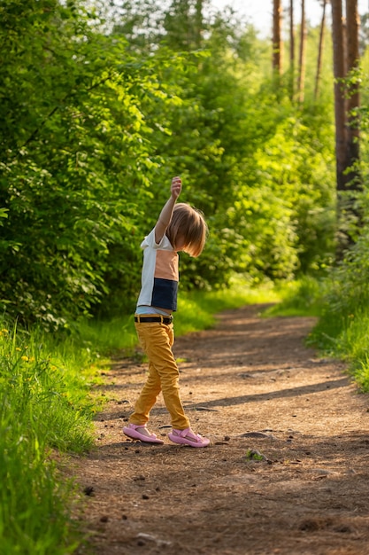 Niña caucásica de años saltando sobre un camino en el bosque