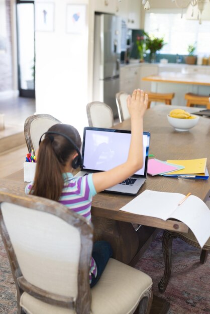 Foto niña caucásica aprendiendo y usando una computadora portátil con espacio para copiar y auriculares en la sala de estar