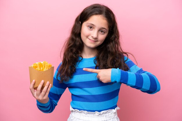 Niña caucásica celebrando un cumpleaños aislada de fondo blanco y apuntándolo