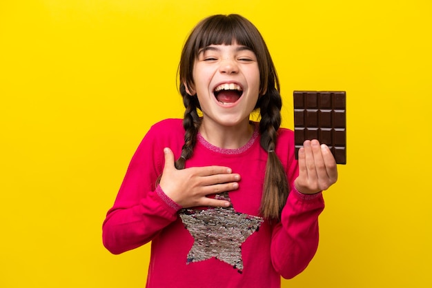 Foto niña caucásica con chocolat aislado sobre fondo amarillo sonriendo mucho