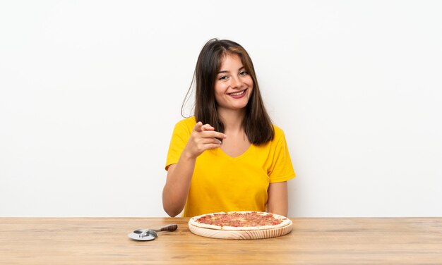 Niña caucásica con un dedo de puntos de pizza a ti