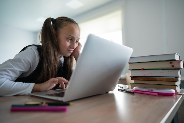 Niña caucásica estudiando en una computadora portátil en un salón de clases