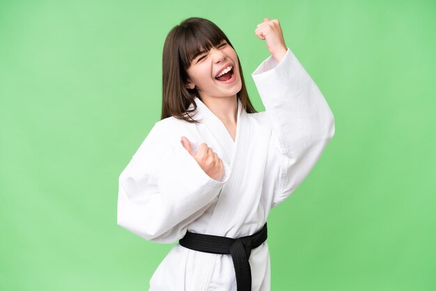 Niña caucásica haciendo karate sobre un fondo aislado celebrando una victoria