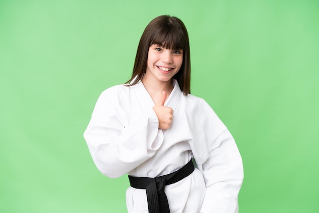 Niña caucásica haciendo karate sobre un fondo aislado dando un gesto de pulgar hacia arriba