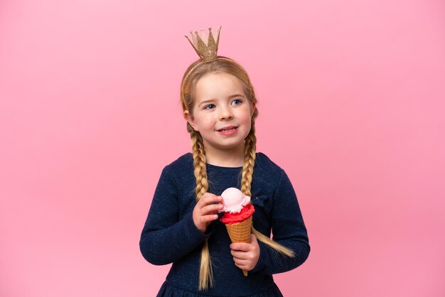 Niña caucásica con un helado de cucurucho aislado sobre fondo rosa