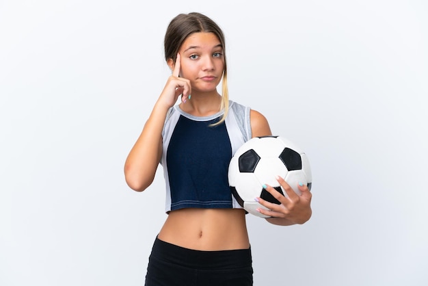 Niña caucásica jugando al fútbol aislada de fondo blanco pensando en una idea