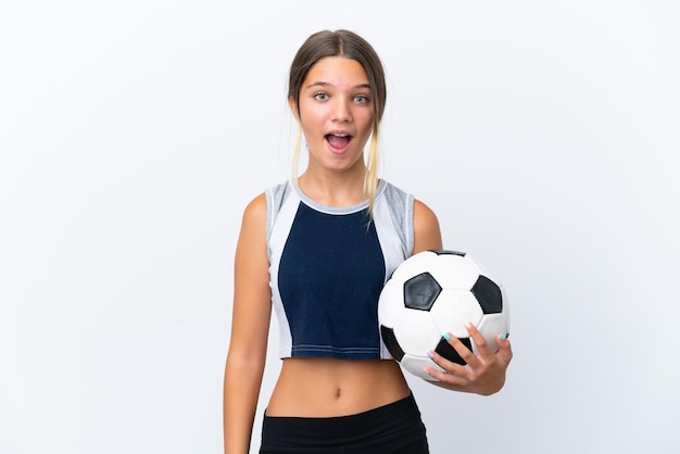 Niña caucásica jugando al fútbol aislado sobre fondo blanco con expresión facial sorpresa