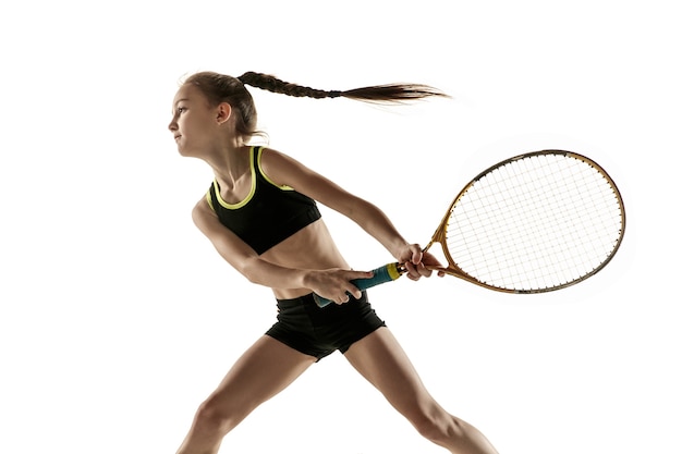 Niña caucásica jugando al tenis aislado sobre fondo blanco.