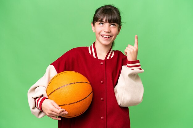 Niña caucásica jugando baloncesto sobre un fondo aislado señalando una gran idea