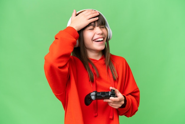 Niña caucásica jugando con un controlador de videojuegos sobre un fondo aislado sonriendo mucho