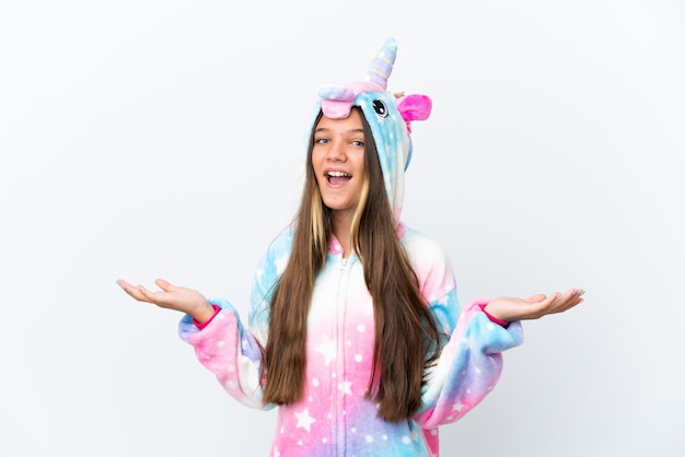 Niña caucásica con pijama de unicornio aislada de fondo blanco con expresión facial sorprendida